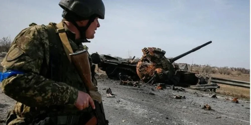 Український військовий біля уламків російського танка у Київській області 28 березня 2022 року